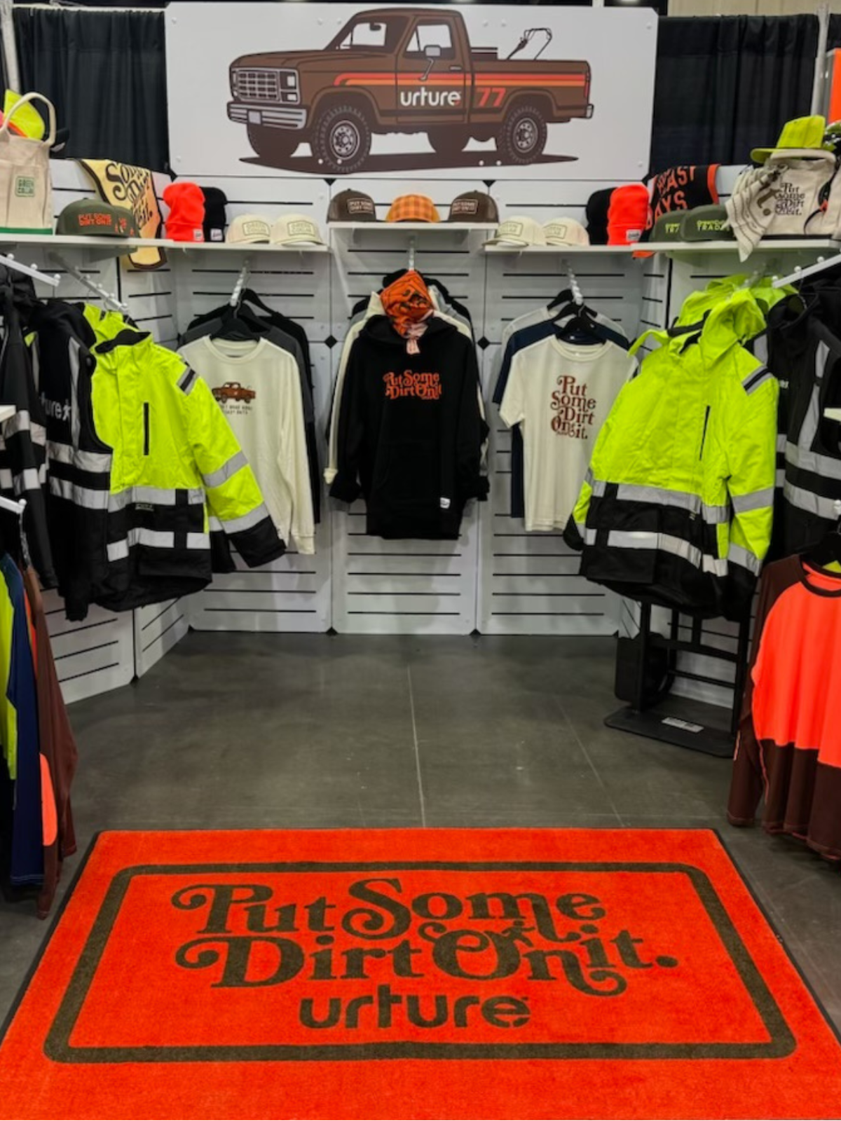 Display of clothing and accessories with a prominent 'urture' logo on a truck graphic in the background.